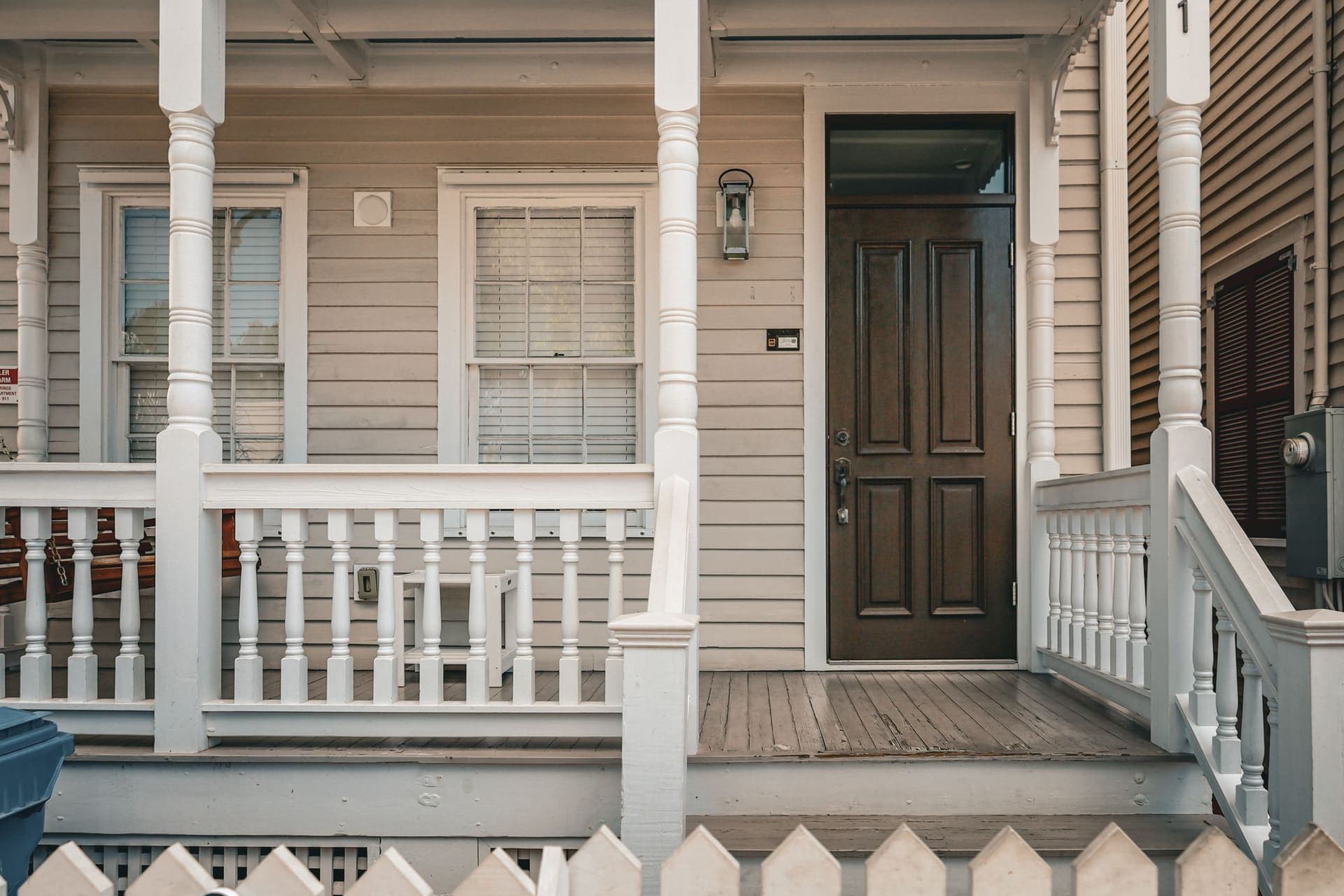 Dark painted front door on a wooden porch with white railings