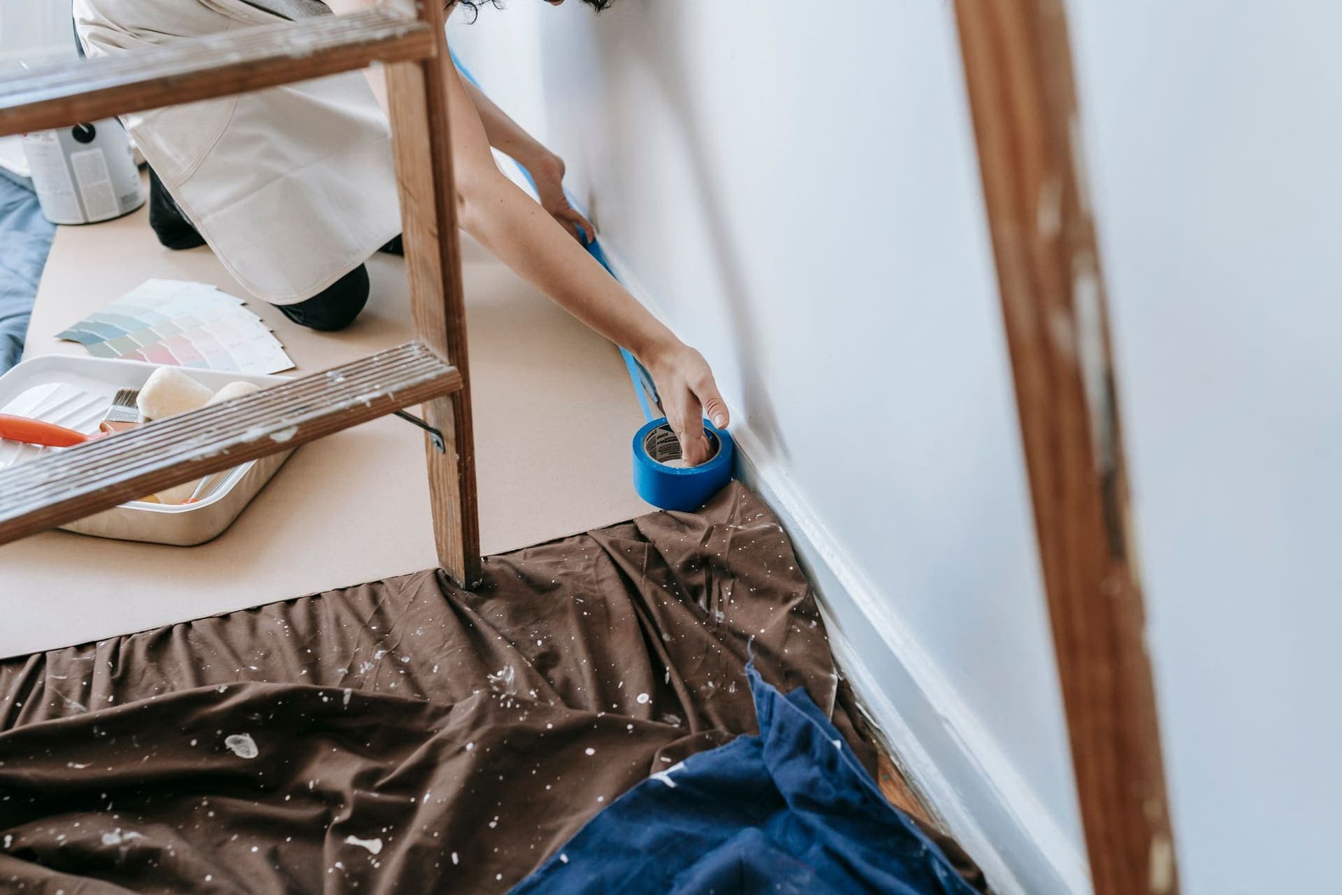 Painter working along the baseboard with drop cloths on the floor