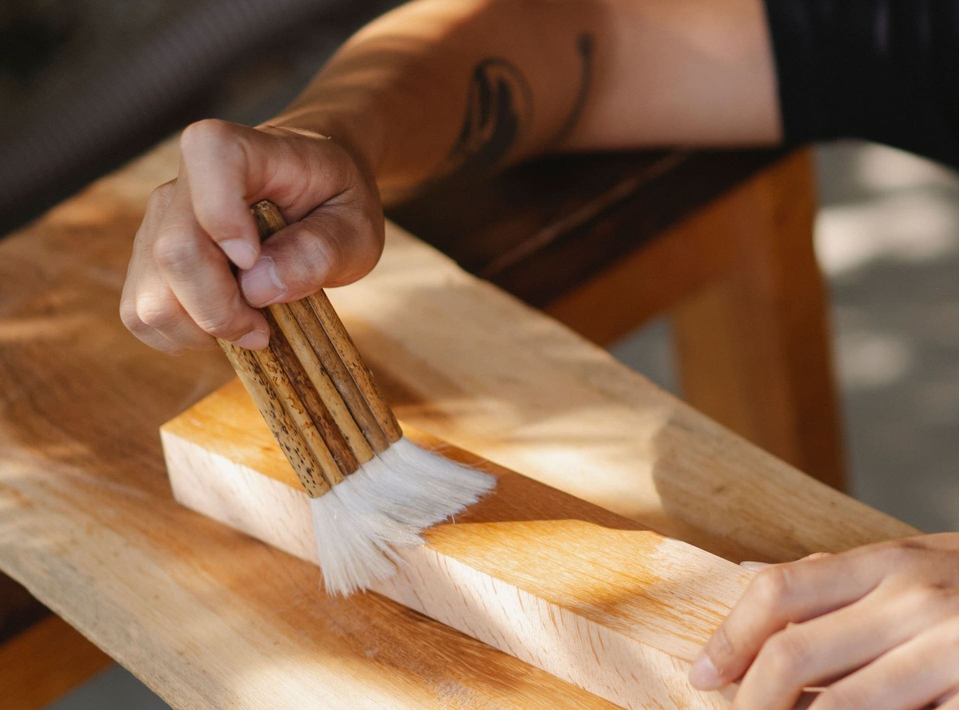 Hands brushing oil finish onto a wooden board
